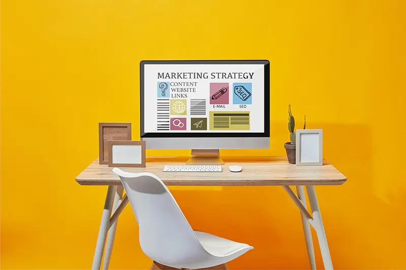an image of a desk with a monitor and a yellow wall behind it