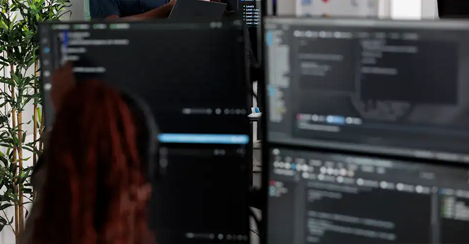 a developer in front of computer monitors with code