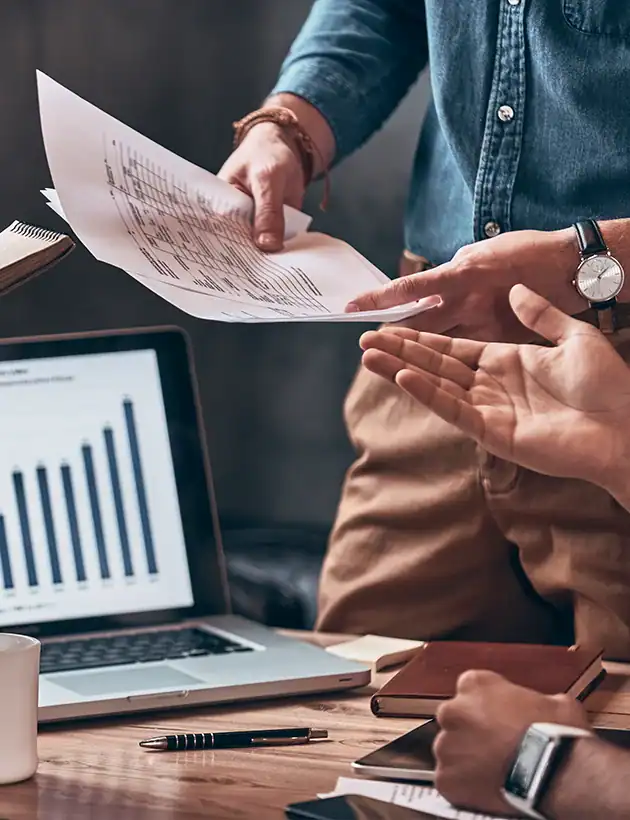 an image of people around a table with laptops ad a growth chart