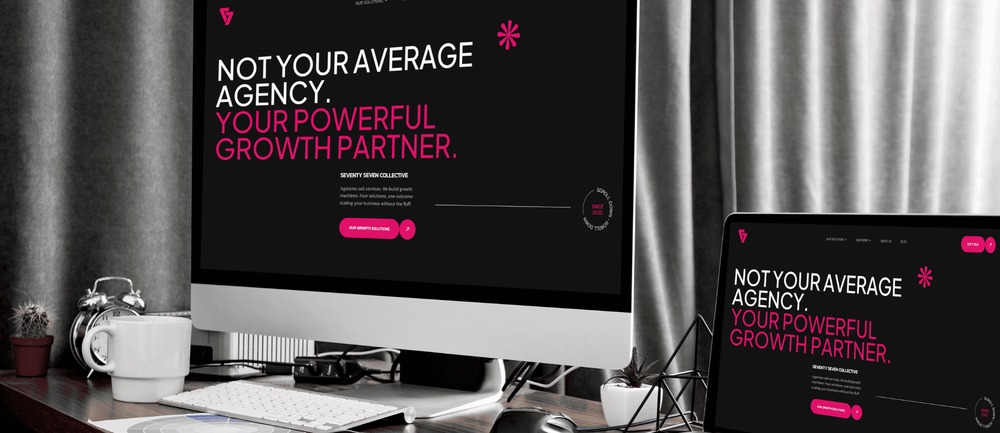 An image of the laptop and desktop with the seventy seven collective website on it.